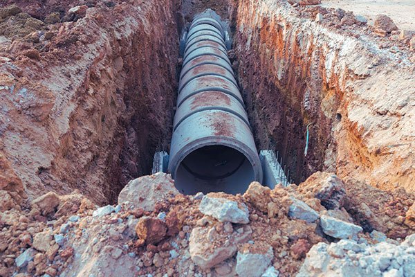 Large drainage pipe installed in excavated trench for land drainage