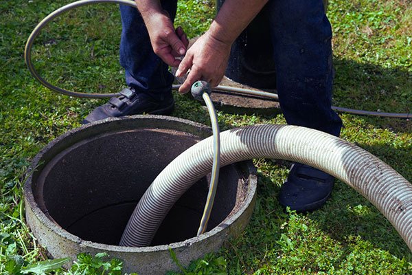 Technician emptying a septic tank with drainage hose